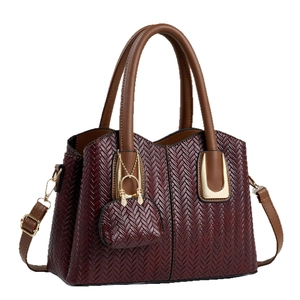 Dunkelrote Handtasche mit Webstruktur, braunen Griffen und Mini-Taschenanhänger