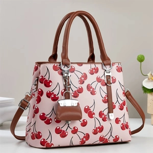 Pink leather handbag with cherry pattern, dark brown handles and detachable shoulder strap