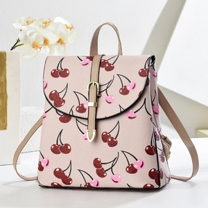 Close-up of pink leather backpack featuring vibrant cherry prints and golden metal buckle