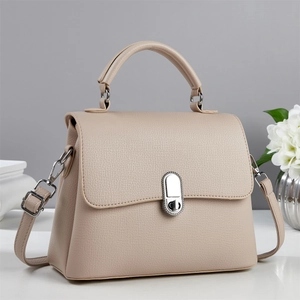 Close-up of beige lychee grain leather handbag with silver metal buckle and round handle