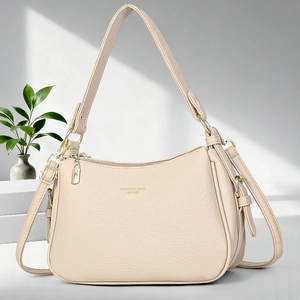 Sac à bandoulière minimaliste en cuir grainé beige sur un support géométrique chic