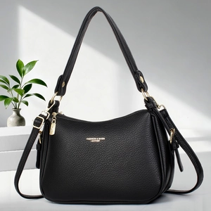 Détail du cuir grainé noir avec accessoires dorés et logo sur un sac à bandoulière chic