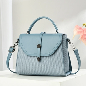 Light blue square handbag with woven texture and metallic clasp on a white stand