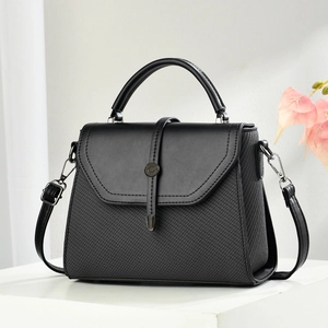 Elegant black textured handbag with adjustable strap displayed in a modern setting
