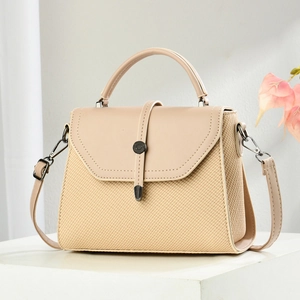 Detail view of beige crossbody bag showing contrasting woven texture and metal buckle accents