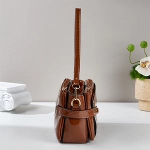 Detail view showing brown patent leather handbag with a functional three-zipper side structure