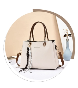 Detail of beige lychee grain handbag with fashion lettering and decorative polka dot ribbon