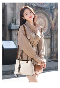 Close-up of beige lychee grain leather tote with brown handles and a stylish plaid scarf