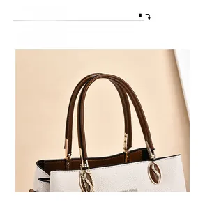 Detail of white lychee grain leather handbag with brown handles and gold hardware