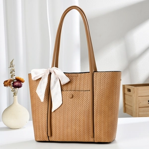 Detail of woven brown tote bag featuring elegant plaid silk scarf handle decoration