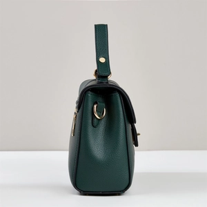 Side view of dark green pebbled leather handbag with gold hardware and smooth edge oil finish