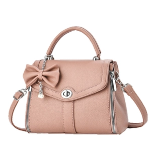 Dusty rose leather crossbody bag with bow pearl charm and top handle in a 45-degree view