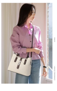 Détail d'un sac à main blanc motif crocodile avec lanières marron et boucle en métal