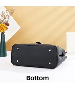 Vue détaillée de la base du sac à main en cuir noir avec quatre clous de protection en argent