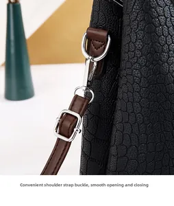 Détail du sac en cuir noir à motif crocodile avec bandoulière brune et boucles argentées