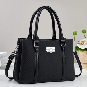 Elegant black herringbone tote bag with leather handles and silver clasp on beige background