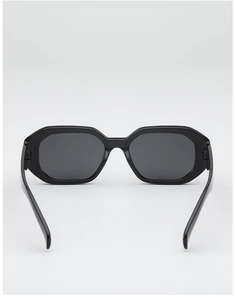 Gros plan de lunettes de soleil hexagonales noires avec verres gris sur fond gris