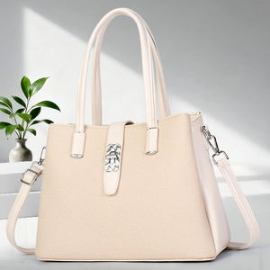 Detail of beige tote bag featuring textured fabric with leather trim and silver metal buckle