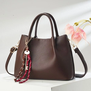 Elegant coffee brown pebbled leather handbag with gold hardware and floral background shadow