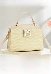 Close-up of cream woven texture and golden B-shaped buckle on elegant shoulder bag
