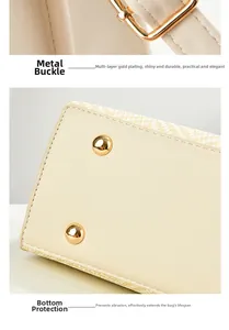Detail of adjustable gold-tone hardware and protective metal feet on cream leather bag
