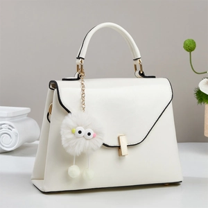 Elegante weiße Handtasche mit schwarzen Kanten, Goldverschluss und süßem Plüsch-Anhänger