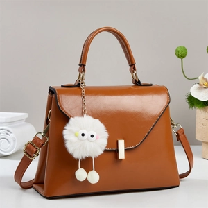 Braune Lederhandtasche mit goldenem Verschluss und süßem Monster-Plüsch-Anhänger