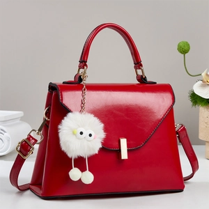 Rote Lederhandtasche mit Goldverschluss und weißem Plüsch-Anhänger für Damenmode