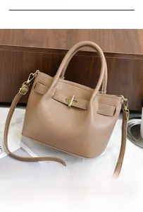 Detail of khaki lychee grain leather handbag with gold metal turn-lock and crossbody strap