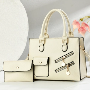 Detail of cream faux leather tote bag set with decorative zippers and metallic hardware