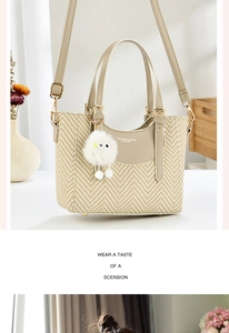 Detail of beige straw texture handbag with plush charm and adjustable strap in lifestyle setting
