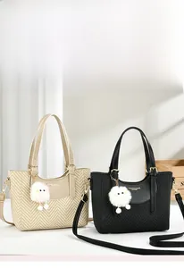 Detail of macaron style beige and black tote bags with woven texture and plush charm