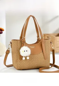 Close-up of brown woven bucket bag featuring gold lettering and cute plush charm detail