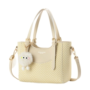 Beige woven Macaron tote bag with plush charm and adjustable strap for crossbody wear