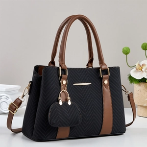 Black herringbone fabric handbag with brown leather straps and gold metal details