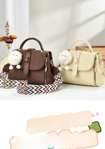 Detail of woven texture handbag with wide jacquard strap and cute plush charm accessory