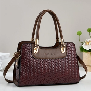 Détail du sac à main bordeaux texturé avec anneaux dorés et gaufrage fashion élégant
