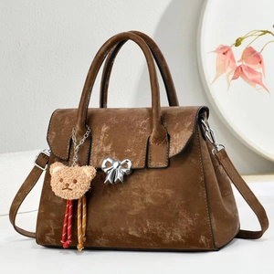 Detail of vintage brown leather handbag with silver bow clasp and cute bear pendant