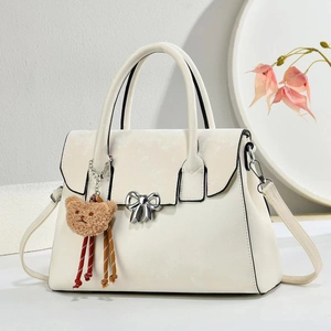 Detail of off-white shoulder bag with silver bow and plush bear charm on white background