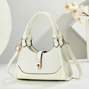 Sac à main élégant beige et gris avec fermoir doré sur un présentoir blanc minimaliste