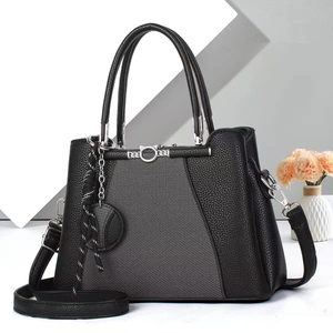 Detail of black tote bag featuring cat ear metal accents and grey diagonal textures