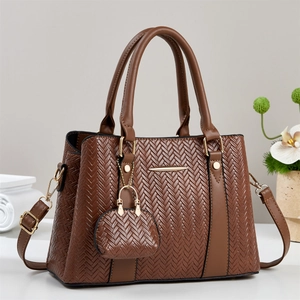 Detail of brown tote bag with herringbone weave, dual handles and mini charm