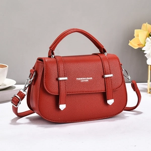 Detail of red lychee textured leather crossbody bag with silver hardware and fashion text