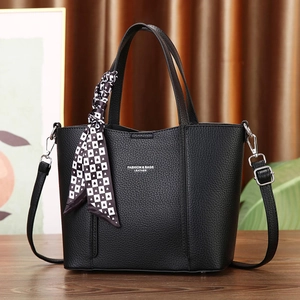 Detail of black pebbled leather tote with fashion text, silk scarf and long shoulder strap
