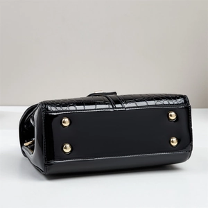 Detail view of gold metal protective feet on black crocodile embossed faux leather bag