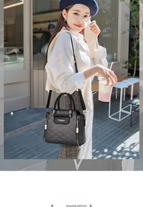 Dettaglio di una borsa tote vintage grigio scuro con monogramma e manici in pelle nera