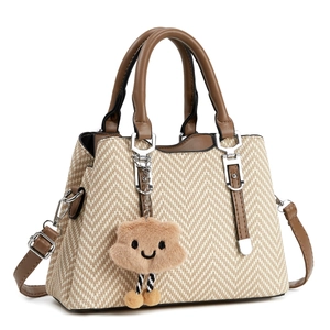 Women's woven shoulder bag in beige and brown chevron pattern with plush charm