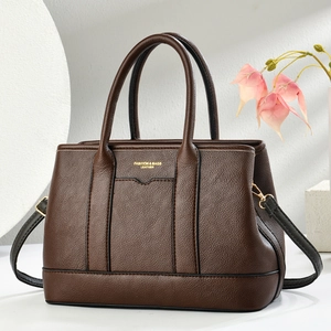Dettaglio di borsa tote in pelle marrone martellata con hardware dorato e tracolla