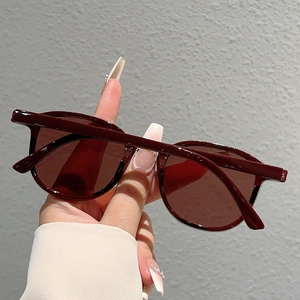 Close-up of minimalist dark red oversized round sunglasses with glossy plastic frames
