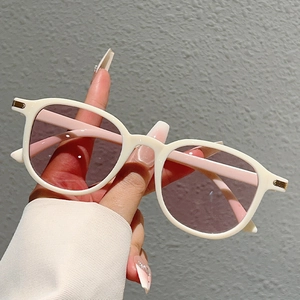 Detail of cream white oversized sunglasses with gold metal accent and light purple lenses